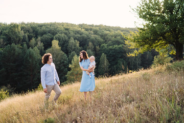 Young happy caucasian couple with little baby boy. Parents and son walking and having fun together. Mother and father playing with toddler outdoors. Family, parenthood, childhood, happiness concept.