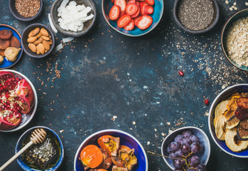 Ingredients for healthy breakfast over dark blue shabby background, top view, copy space. Fresh and dried fruit, chia seeds, oatmeal, almonds, honey. Clean eating, vegan, healthy food, dieting concept