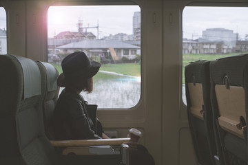 Enjoying travel. Young pretty woman traveling by the japan classic train from hakata to yufuin Japan (Limited Express Yufuin no Mori) sitting near the window. vintage filter.