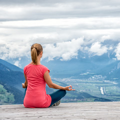 Fototapeta na wymiar young woman meditate on top of the mountain