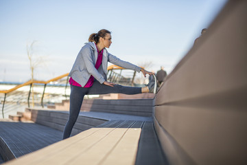 Morning exercise near the river. Young woman on recreation and jogging.
Warm up and stretch muscles before the morning exercise by the river