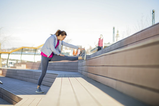 Morning exercise near the river. Young woman on recreation and jogging.
Warm up and stretch muscles before the morning exercise by the river