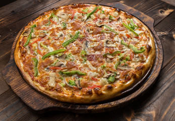 Delicious pizza with mushrooms - thin pastry crust isolated at wooden background on wooden desk