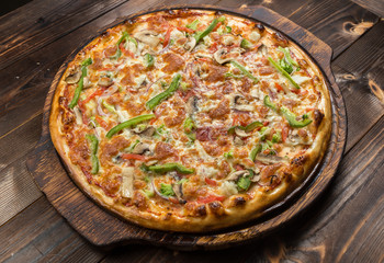 Delicious pizza with mushrooms - thin pastry crust isolated at wooden background on wooden desk