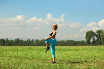 Beautiful sport woman doing stretching fitness exercise in city park at green grass. Yoga postures