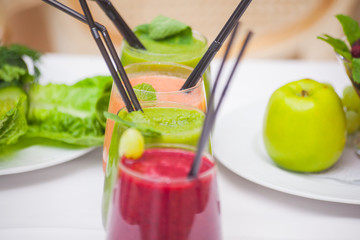 Red and green healthy smoothies with fresh ingredients on table.