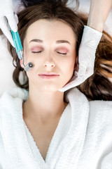 Making dry needlying procedure on woman's face in the cosmetology office