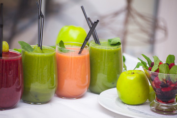 Red and green healthy smoothies with fresh ingredients on table.