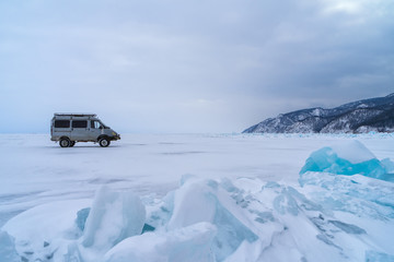 A van stopped at blue frozen water covered with snow at Baikal lake during winter