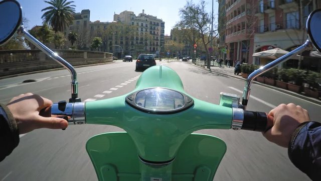 POV, man uses his electric automatic scooter for commute within city traffic at daylight summer time, driving through big roundabout, turning and overtaking cars