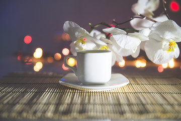 cup of coffee on a bamboo napkin on a background of white orchids 