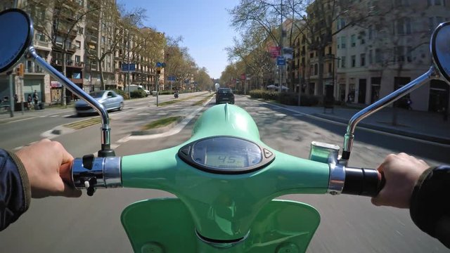 Pov view on action cam, driving small electric motorbike through urban roads at summer sunny day