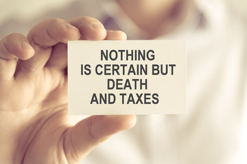 Businessman holding NOTHING IS CERTAIN BUT DEATH AND TAXES message card