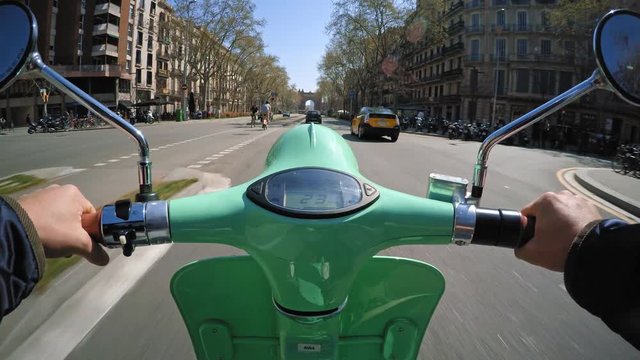 Pov view on action cam, driving small electric motorbike through urban road next to bicycle lane on left cide and bus and taxi lane on right, at summer sunny day