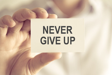 Businessman holding NEVER GIVE UP message card