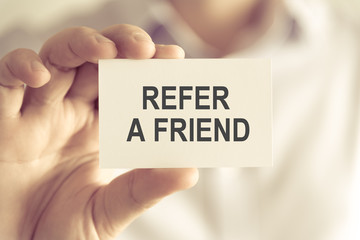 Businessman holding REFER A FRIEND message card
