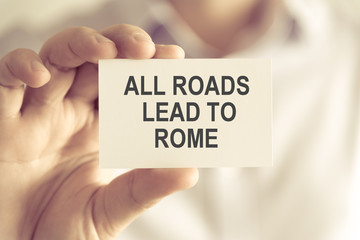 Businessman holding ALL ROADS LEAD TO ROME message card