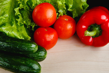 Fresh vegetables on the table: red pepper, lettuce, cucumber, tomatoes. Cutting board