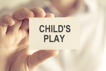 Businessman holding CHILDS PLAY message card