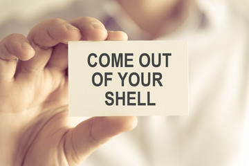 Businessman holding COME OUT OF YOUR SHELL message card