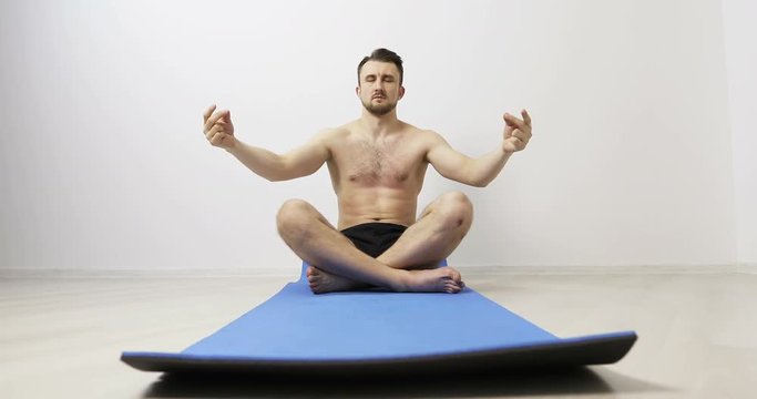 Male doing yoga on exercise mats.