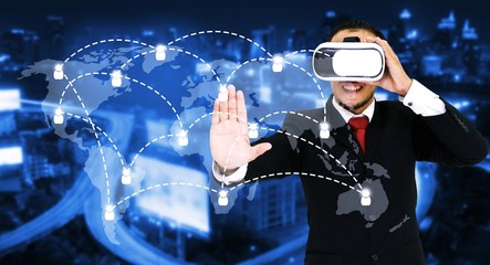 asian businessman wearing VR virtual reality headset, business and technology concept for future with world map social media connection on blurred night city background color tone effect wide screen
