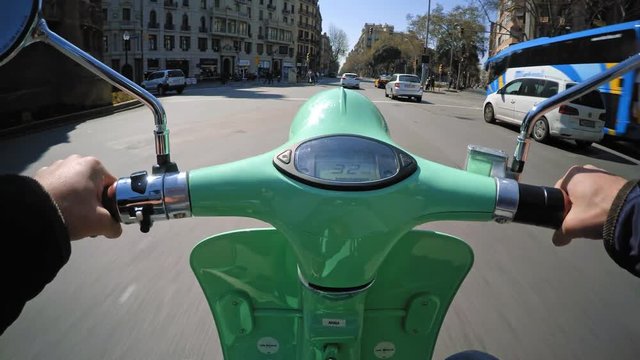 Pov view, riding small electric scooter for commute trips in urban traffic, overtaking cars and turning on big roundabout at sunny spring day in town