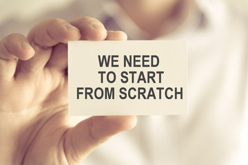 Businessman holding WE NEED TO START FROM THE SCRATCH message card
