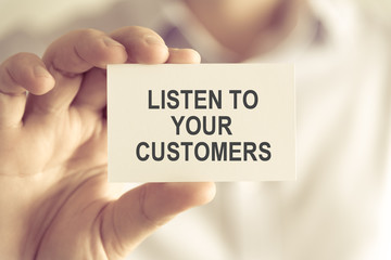 Businessman holding LISTEN TO YOUR CUSTOMERS message card - 141635472