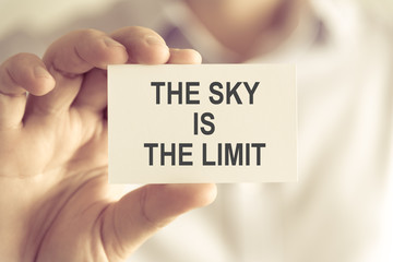 Businessman holding THE SKY IS THE LIMIT message card
