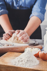 Woman baker knead yeast dough with eggs and flour