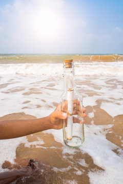 Bottle with a message in the hand on the beach.