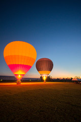 Obraz premium Two big balloon ready to take off at green field in twilight sky