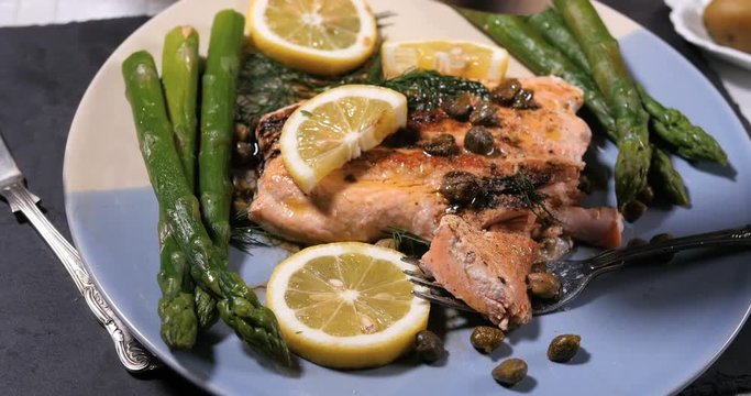 Sprinkling black pepper over a delicious roasted organic salmon with capers and dill