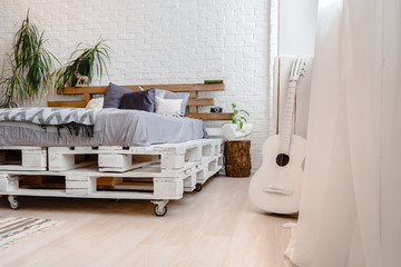 White interior with pallets, bed and guitar