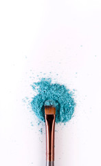 Makeup brush background with eyeshadow sprinkled on white