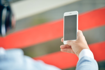 Man with headphones holding mobile smart phone on outdoors background