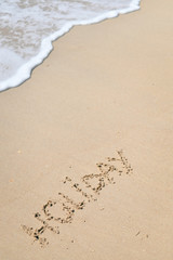 Top view on inscription Holiday on sea sand beach with the sun rays against wave foam. vacation concept