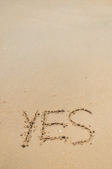 Yes sign written in sand on beach texture top view close up