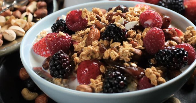 Dolly panning view of a breakfast of cereals with berries, dry fruits and milk