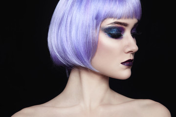 Portrait of young beautiful woman with colorful fancy make-up and violet wig