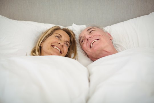 Happy senior couple lying on bed