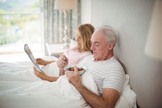 Senior man having breakfast on bed - Powered by Adobe