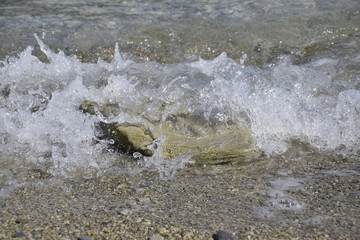 Sea waves run ashore, bubbling and stone covering