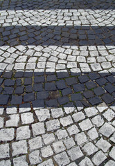 Fototapeta premium Black and white stripes on the pavement of stones.