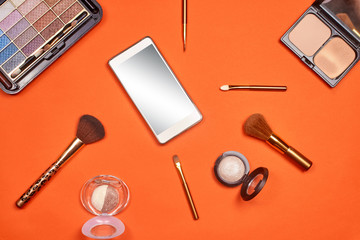 Flat lay, top view feminine table desk isolated on white. Workspace with cosmetics, phone, glasses, lipstick, nail lacquer, watches, mascara and eyeshadow in gold. Golden and black tones.