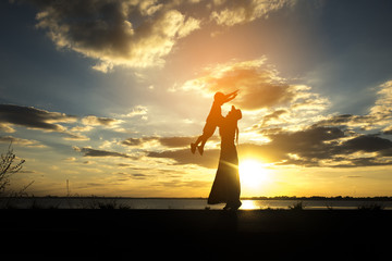 Silhouette of mother and kid. mother and daughter are playing happily together. The backdrop is the sunset.