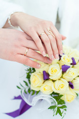 Жених и невеста держат руки на фоне букета из белых роз