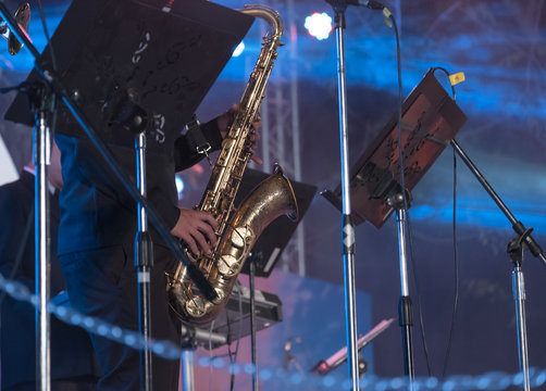 Outdoor concert / View of musician blowing saxophone in outdoor concert at night. Movement.