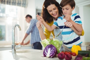 Mother and son mixing the salad in kitchen